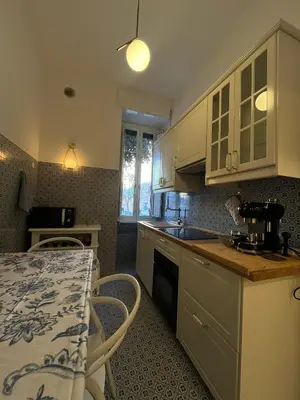 a kitchen with white cabinets and a sink and a table at Charming Apartment in San Pietro in Rome