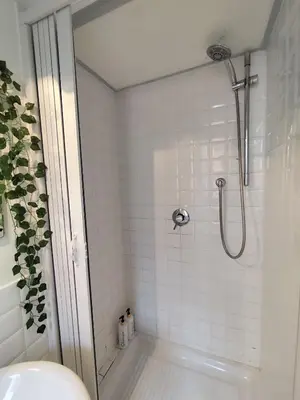 a bathroom with a shower with white tiles at Colosseum Studio Flat blue in Rome