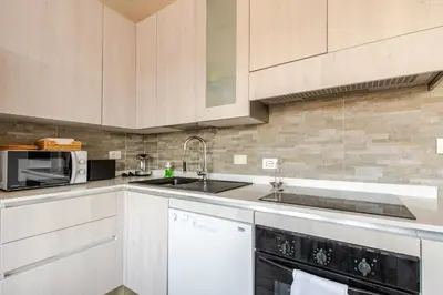 a kitchen with white cabinets and a sink and a microwave at Luminoso Attico Piazza Bologna - Metro Policlinico in Rome