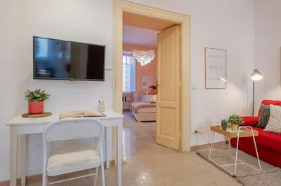 a living room with a red couch and a tv on a wall at La Casetta di San Giovanni in Rome