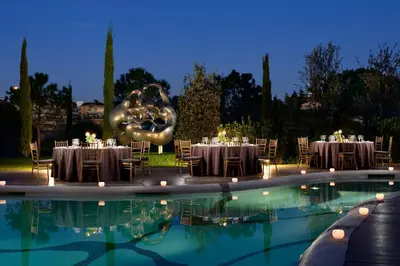 a restaurant with tables and a swimming pool at night at A.Roma Lifestyle Hotel in Rome