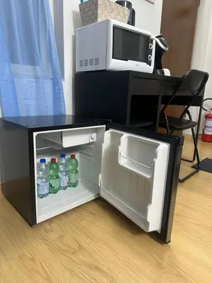 an open refrigerator with bottles of water in front of a microwave at Alloggio Fiorella in Rome