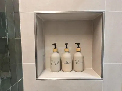 three bottles in a bathroom shelf in a shower stall at Deltis Boutique Apartments in Rome