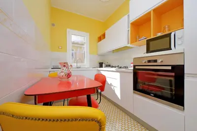 a kitchen with a red table and yellow chairs at 4BNB - Monteverde Chic & Comfort in Rome