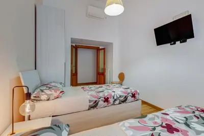 a bedroom with two beds and a flat screen tv at 3-Bedroom Home Near Trastevere Station in Rome