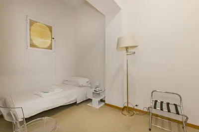 a white room with a bed and a lamp and a chair at Family Stay in Trastevere in Rome