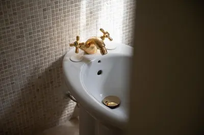 a bathroom with a gold faucet on a sink at Trastevere Rooftop Terrace Courtyard Loft in Rome