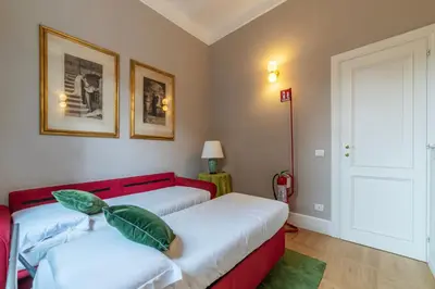 a bedroom with two beds and a red couch at Santa Maria alle Fornaci - FromHometoRome in Rome