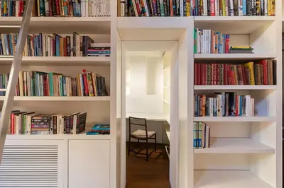 a library with white shelves filled with books at Luce Trastevere Retreat by Romeloft in Rome