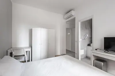 a white bedroom with a bed and a tv at Porta Furba Apartment in Rome