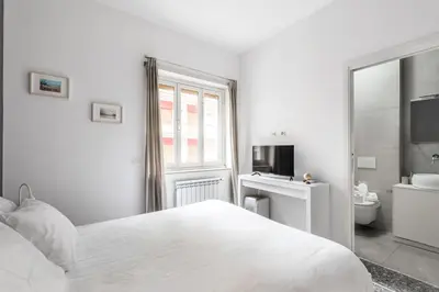 a white bedroom with a bed and a bathroom at Porta Furba Apartment in Rome