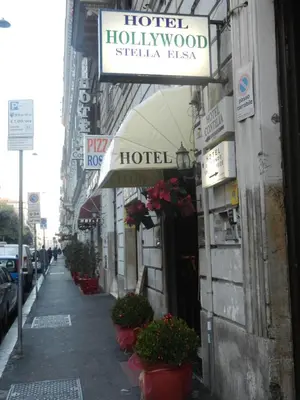 a sign for a hotel on a street with flowers at Hotel Hollywood in Rome