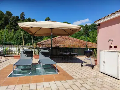a patio with an umbrella and chairs and a grill at Domus Monamì Dreams & Terrace in Trastevere in Rome