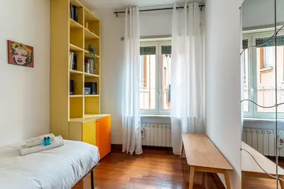 a bedroom with a bed and a table and windows at iFlat The Roman House - Spacious & Central Apt in Rome