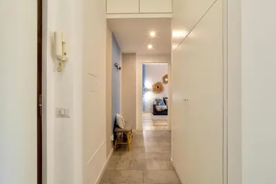 a hallway with white walls and a hallway with a chair at Grazia Appartamento Moderno & Chic a Tiburtina in Rome