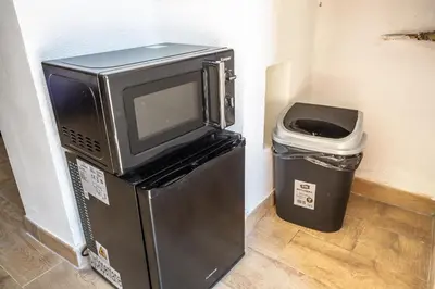 a tv sitting on top of a refrigerator next to a trash can at Eco Retreat -Sauna & Garden in Rome