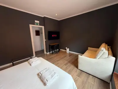 a bedroom with a white bed and a couch at San Lorenzo Elegance Suites - just steps from the Colosseum in Rome