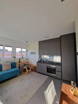 a living room with a blue couch and a kitchen at La casetta del villaggio - Cozy apartment in Flaminio in Rome