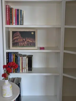 a book shelf with books and a vase on a table at Interno7 in Rome