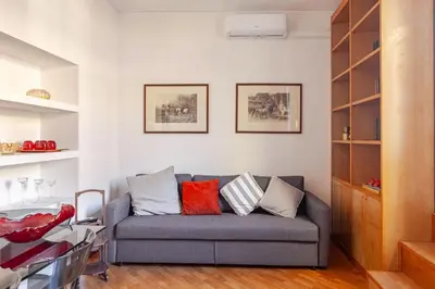 a living room with a gray couch with colorful pillows at Luxury Penthouse with Terrace by Spanish Steps in Rome