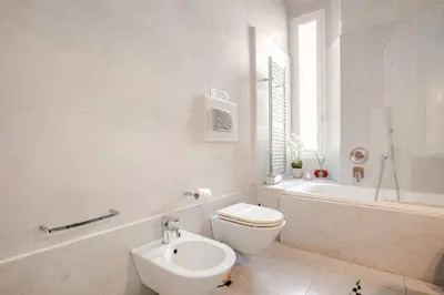 a white bathroom with a toilet and a bath tub at Suite Testaccio in Rome