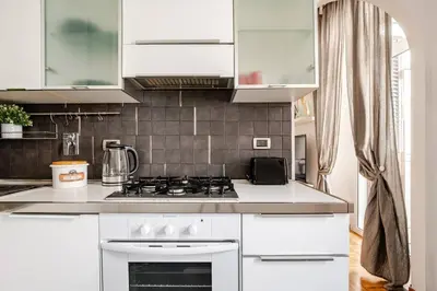a white kitchen with a sink and a stove at Suite Testaccio in Rome