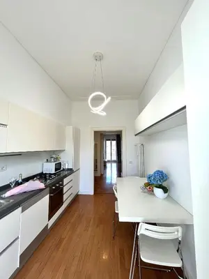 a kitchen with white cabinets and a table with chairs at Roma Luxury Apartment in Rome