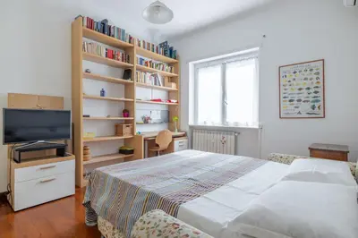 a bedroom with a bed and a tv and bookshelves at Roman Retreat Near the Appian Way & Catacombs in Rome