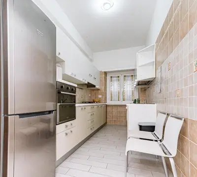 a kitchen with white appliances and white chairs at A Casa di Federico e Nikki - Vatican City - Metro Baldo degli Ubaldi in Rome