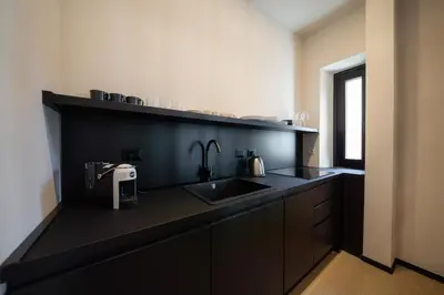 a kitchen with a sink and a black counter top at Courtyard Doria Comfort & Style at Vatican Museums in Rome