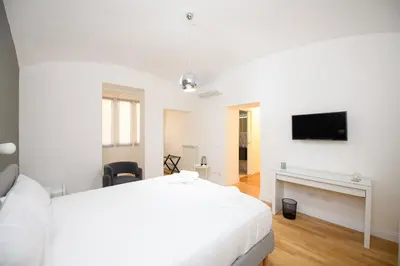 a white bedroom with a white bed and a tv at Boncompagni Serenity Suites in Rome