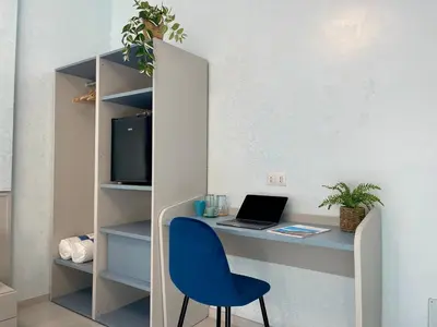 a desk with a laptop and a blue chair at Stellar Stays in Rome