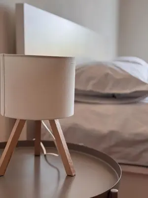 a white lamp sitting on a table next to a bed at Alberto's panoramic flat in Rome