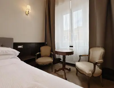 a bedroom with a bed and two chairs and a table and a window at Belle Epoque in Rome