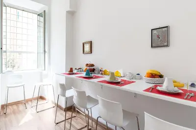 a white kitchen with a long counter with chairs at Rome Center Rooms in Rome