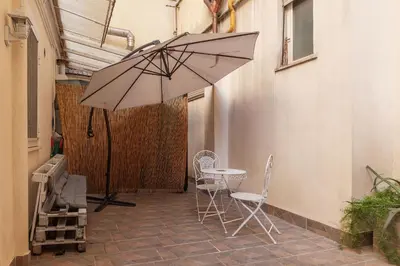 a patio with a table and chairs and an umbrella at GuestHost - Garbatella Comfy Apartment in Rome