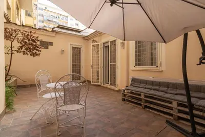a patio with a table and chairs and an umbrella at GuestHost - Garbatella Comfy Apartment in Rome