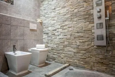 a bathroom with a toilet and a stone wall at The 150 Home - Homkeey Apartments in Rome