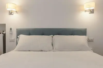 a bed with white pillows and a blue headboard at 2-Bedroom Roman Gem in Rome