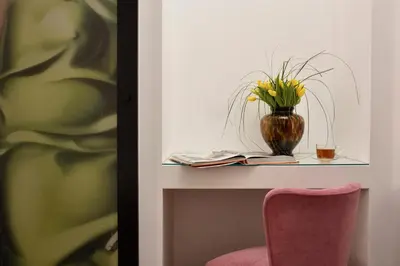 a table with a vase of flowers and a chair at Palazzo Tridente Rooms in Rome