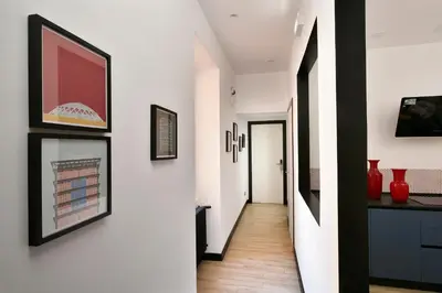 a hallway with white walls and black framed art at Palazzo Tridente Rooms in Rome