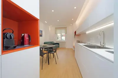 a kitchen with white counters and an orange wall at 4BNB - Charming Giuliana Apartment in Rome