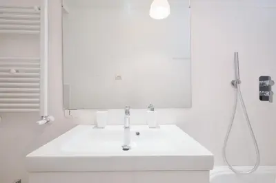 a white bathroom with a sink and a mirror at Vatican Museums - Modern flat with Wi-Fi & Netflix in Rome