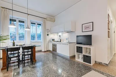 a kitchen with white cabinets and a table with chairs at Kenzia Suite Aventino in Rome