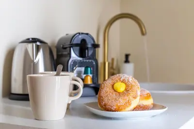 two donuts on a plate next to a cup of coffee at iFlat Stylish & Cozy apt in the Heart of Monti in Rome