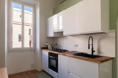 a kitchen with white cabinets and a sink and a window at GuestHost - Roma San Lorenzo Apartment in Rome