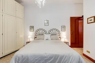a white bedroom with a large bed with two lamps at Rossini Home in Rome