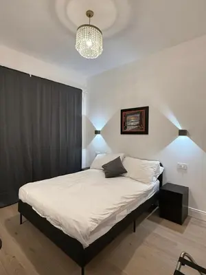 a bedroom with a bed with white sheets and a chandelier at Vita Lux Vatican Suites in Rome