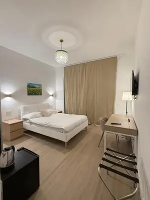 a white bedroom with a bed and a desk at Vita Lux Vatican Suites in Rome