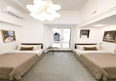 two beds in a white room with a chandelier at Vatican Prestige Suite 